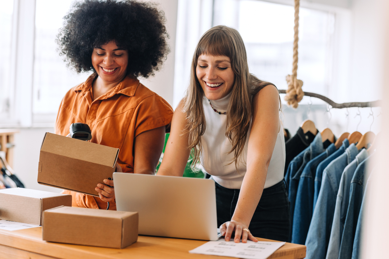 Happy young businesswomen preparing delivery parcels in a thrift store